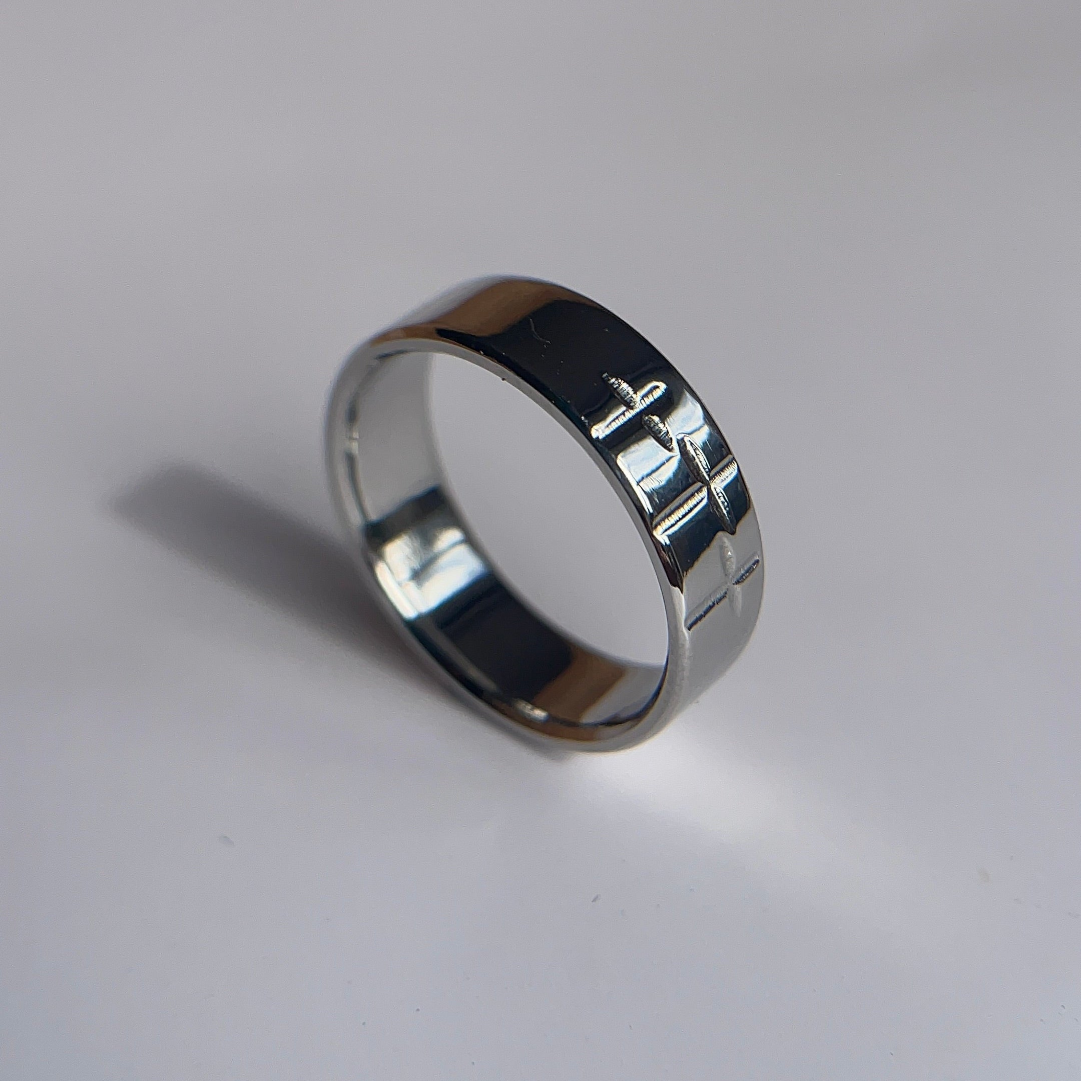 A polished silver band ring with engraved Hebrew lettering, resting on a plain white surface.